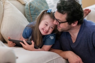 Father and daughter with down syndrome using a tablet