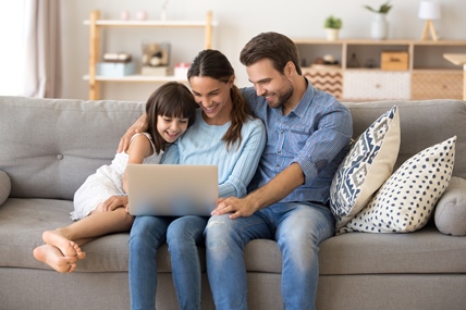 Family of three sitting in family room looking at a laptop