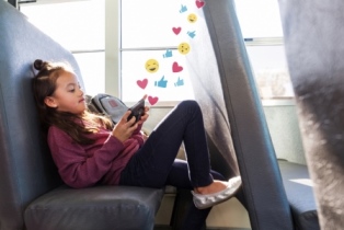 Girl on phone on the school bus with animation of emojis above her head