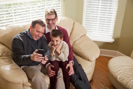 A male same sex couple with their son take a selfie