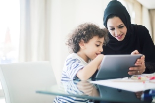 A Muslim woman and her small child look at the screen of an tablet
