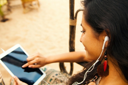 A teen girl with earbuds in looks at an ipad screen