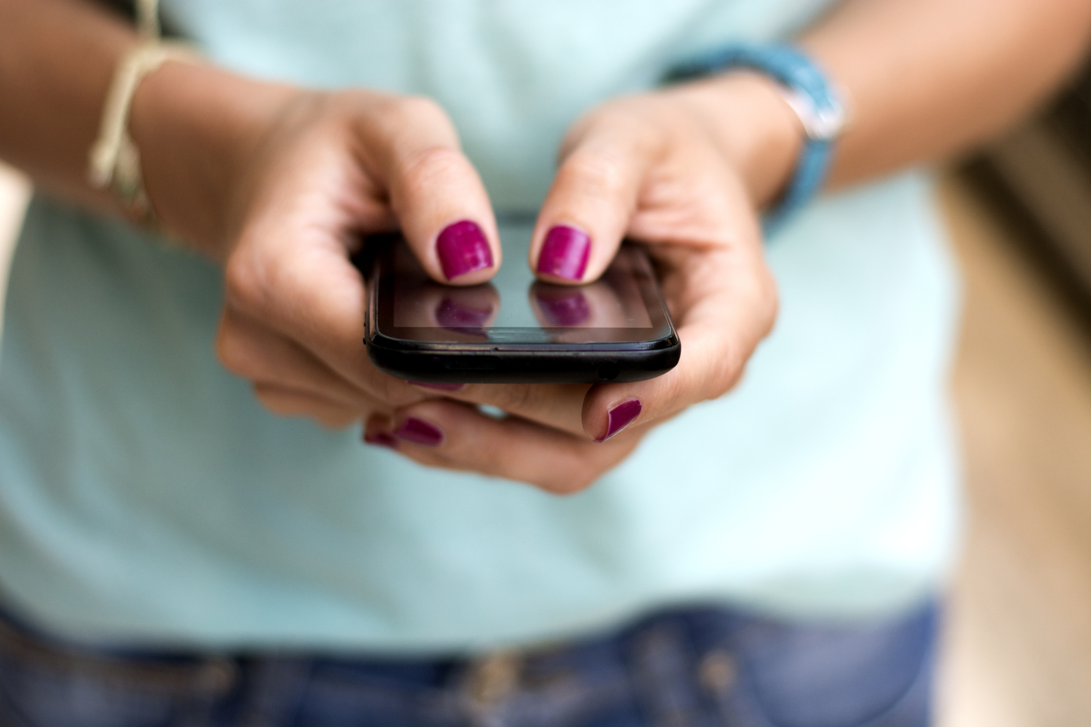 A close up photo of the hands of a teen girl texting