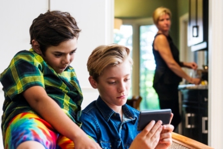 Mom looking over her shoulder at two boys looking at phone