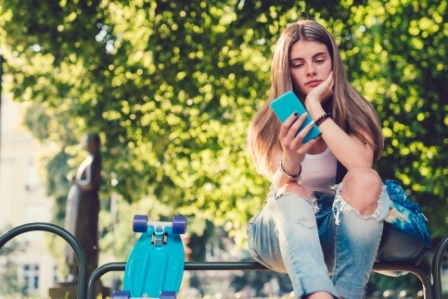 A young girl sits looking at her phone