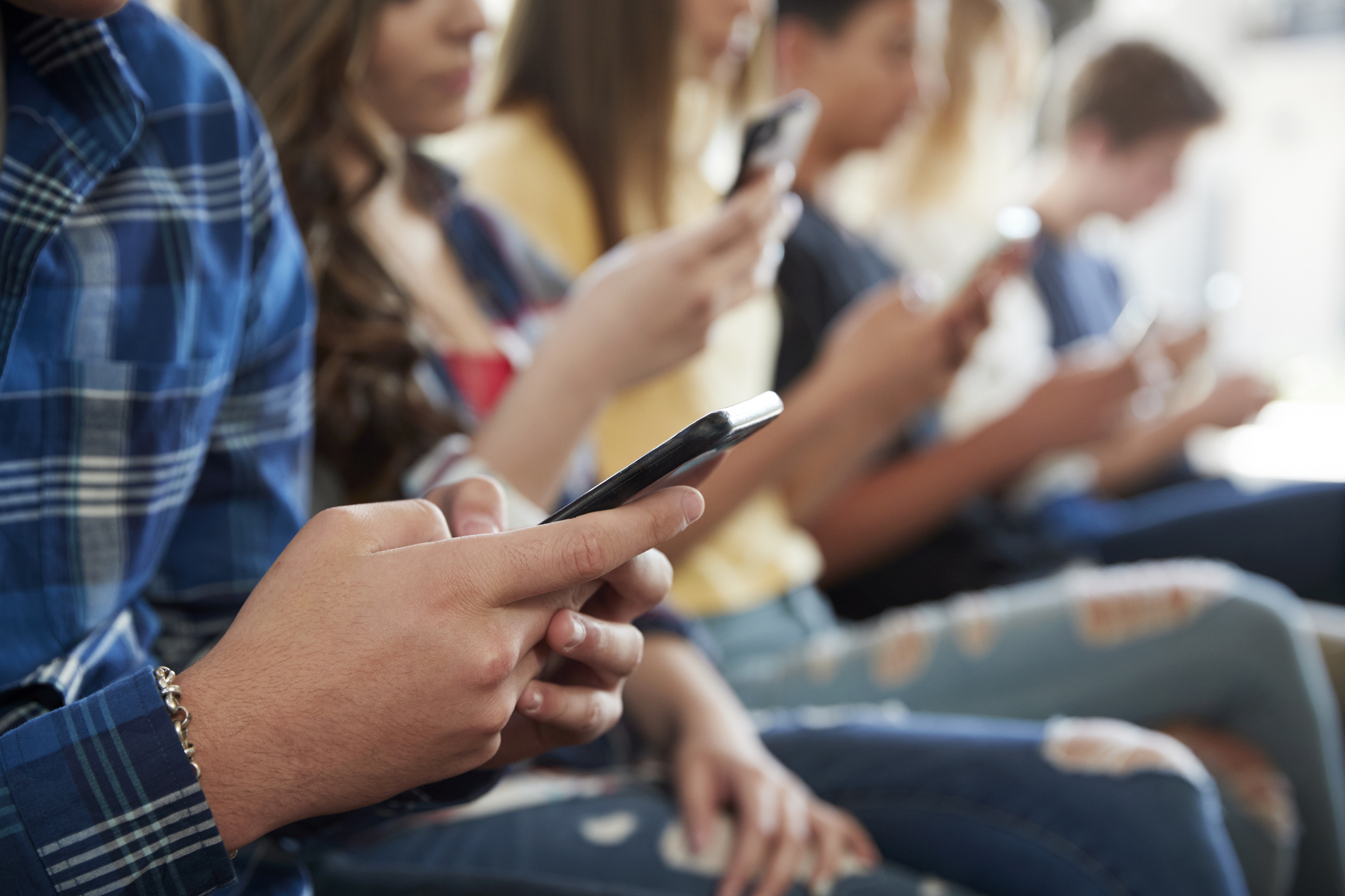 A close up of the hands of multiple teens who are texting