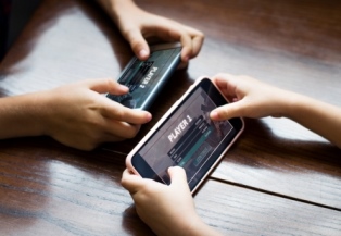 Photo of the hands of two youth with phones playing a game