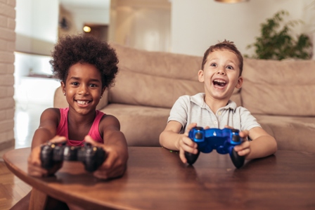 A young boy and a young girl laugh as they play video games