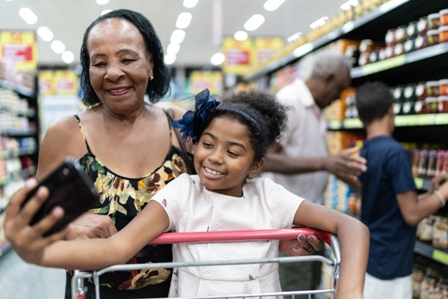 An african american older woman takes a selfie with her granddaughter in a grocery store