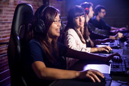 Teen girls sit at computers gaming