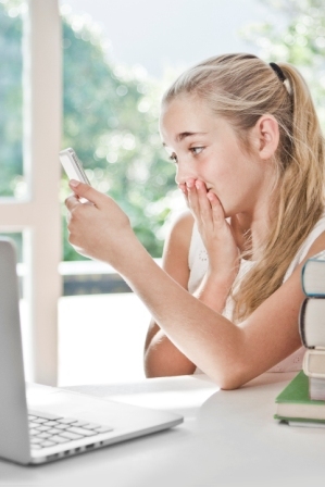 A shocked looking girl looks at her iphone screen