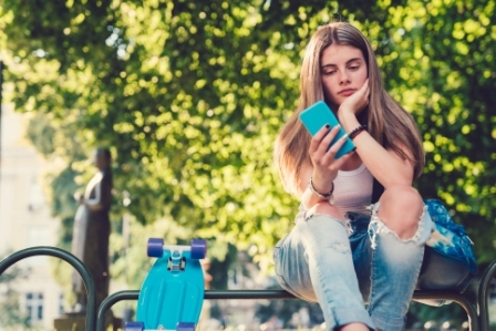 A young girl sits looking at her phone