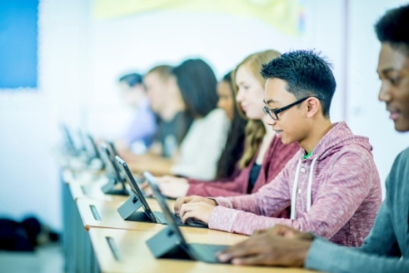 A several students at a long table, each on a computer