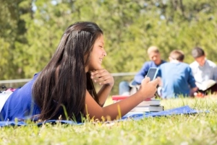 Indigeneous girl in outdoor summer setting using a smartphone